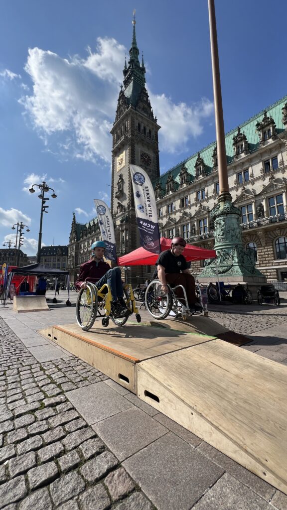 Zwei Rollstuhlfahrer auf mobilen Skate Rampen vor dem Hamburger Rathaus.